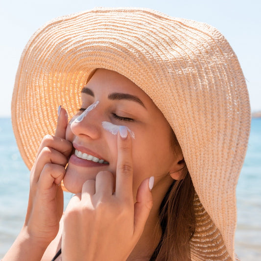 Woman at the beach is putting sunscreen on her face